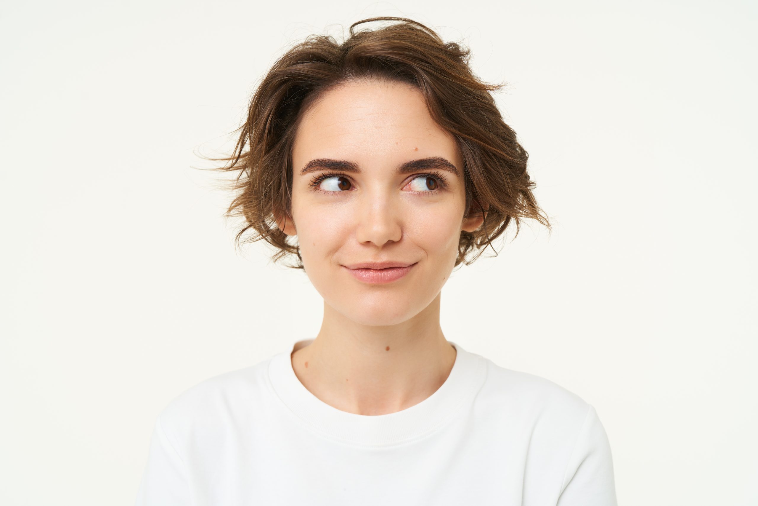 Close up portrait of brunette girl with short haircut, smiling and looking happy, posing over white background.